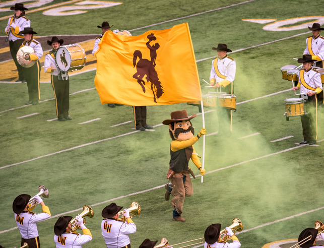 Pistol Pete running with a Bucking Horse flag down a football field