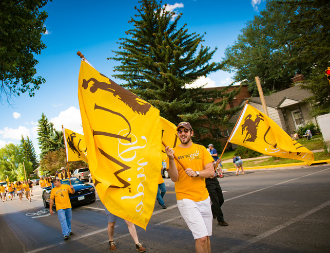 Individual walking with an UW Flag in the Homecoming parade
