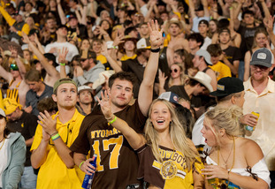 UW students hold up a four with their fingers, signifying the fourth quarter at a UW football game