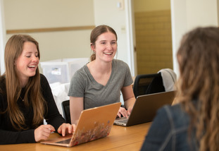 UW students work on their laptops, seated together at a table