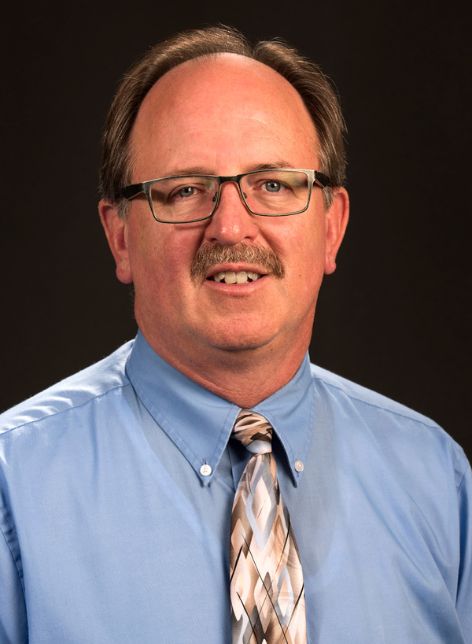 A man in a light blue shirt with a checkered tie.