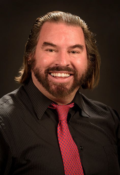A man in a black shirt with a red tie.
