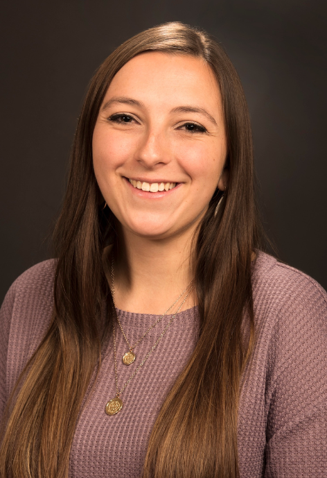 Hannah Downey smiles for a headshot in a purple sweater