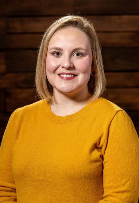 Michaela Doyle smiles for a photo in a yellow sweater