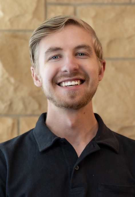 Tyler Gross smiles in a black polo