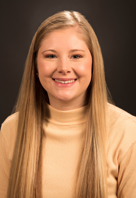 Shelbey Gunter smiles for a photo in a yellow turtle neck