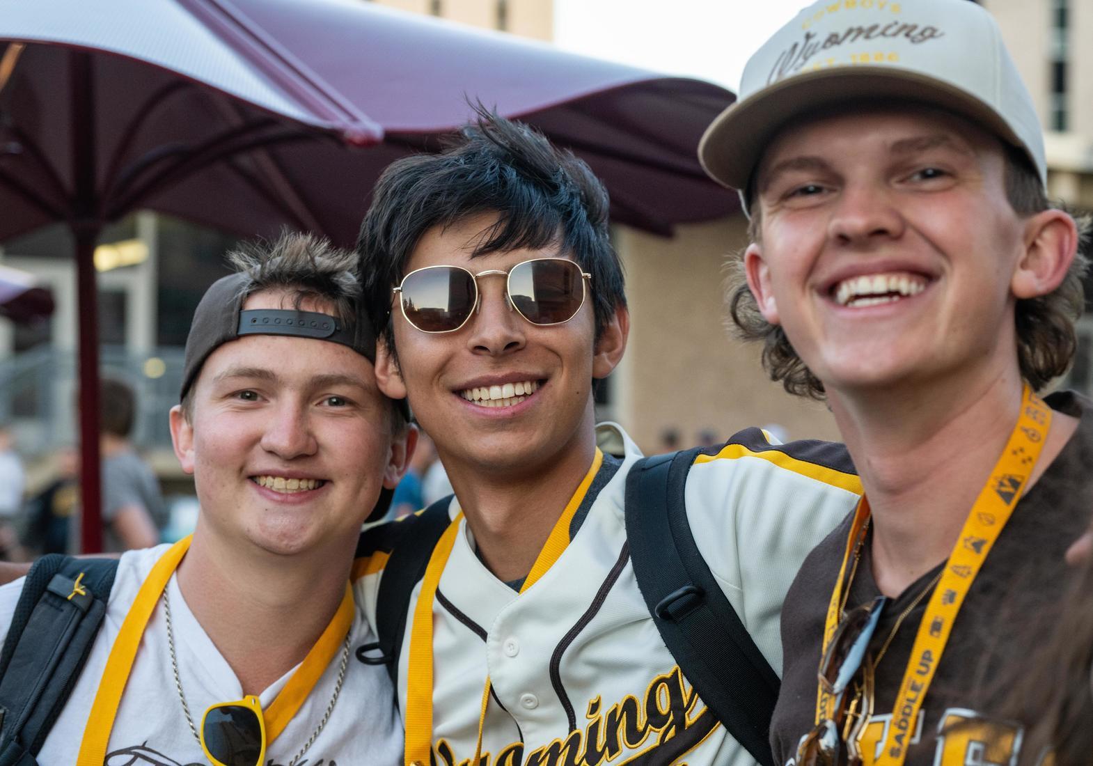 Three male students posing for a group shot wearing UW gear.