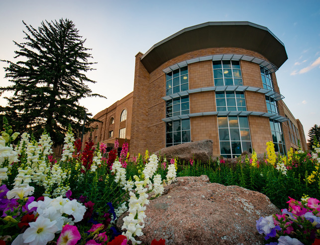 The east side of Half Acre Recreation and Wellness Center with flowers in full bloom at sunset