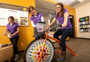 Campus Recreation Wellness Center employees use a bike to power a blender and make a smoothie