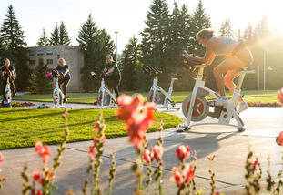 A UW group fitness instructor leads a cycling class outdoors on a sunny day in Laramie