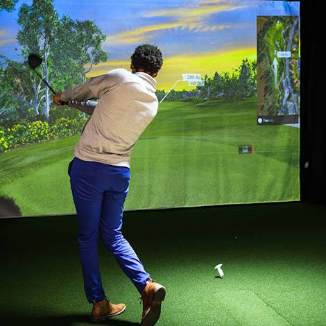 An individual uses the golf simulator in Half Acre Gym
