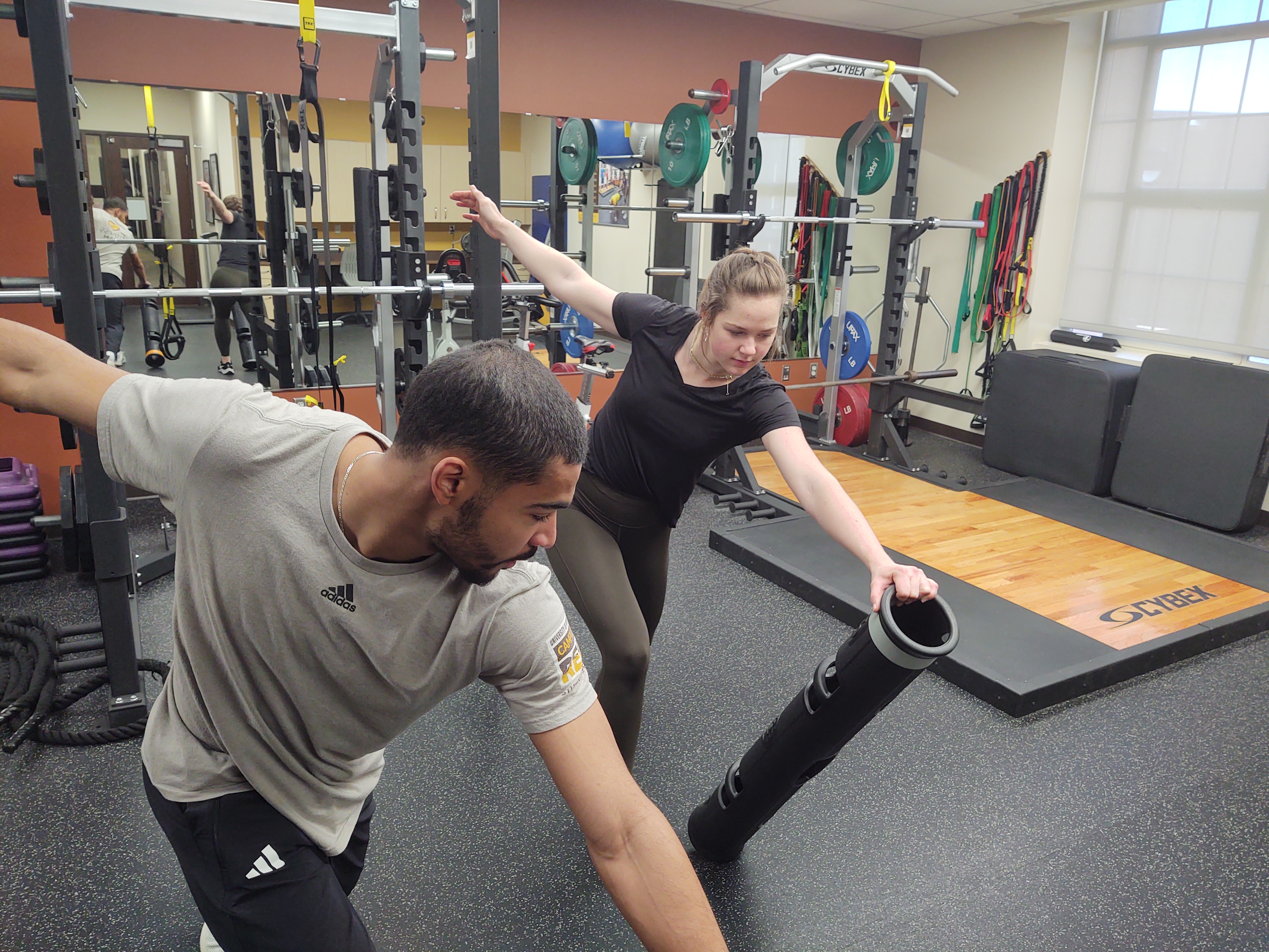 A personal trainer works with clients in Half Acre Gym