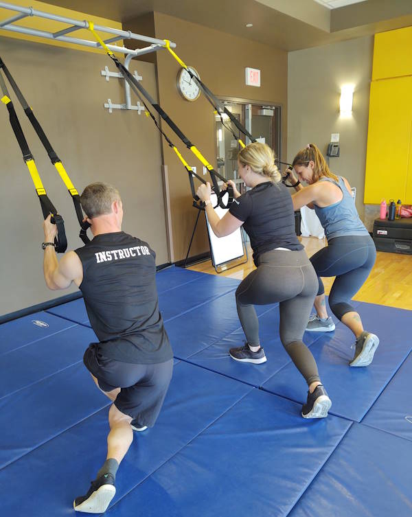 A personal trainer works with clients in Half Acre Gym