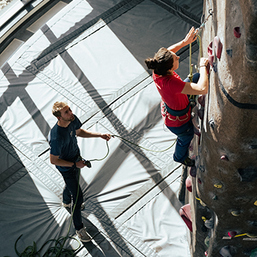 Two students climb at the climbing wall in Half Acre Gym