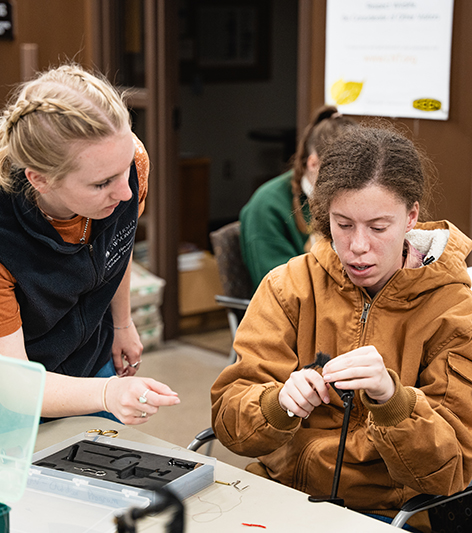 A student leader instructs another student at a fly tying clinic