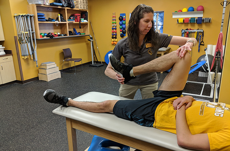 An athletic trainer works with a student