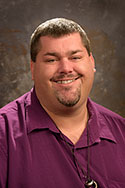 Jim Osborn smiling in front of a grey background