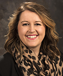 Kaila Hine smiling in front of a grey background