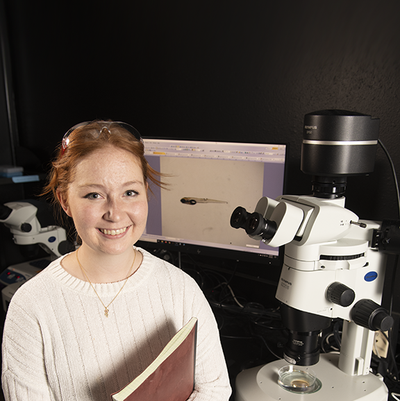 Woman standing next to microscope
