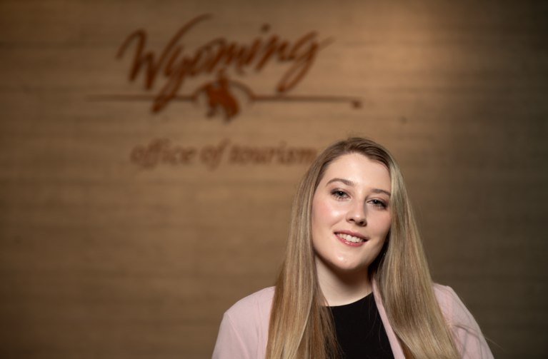 Person posing in front of Wyoming tourism sign