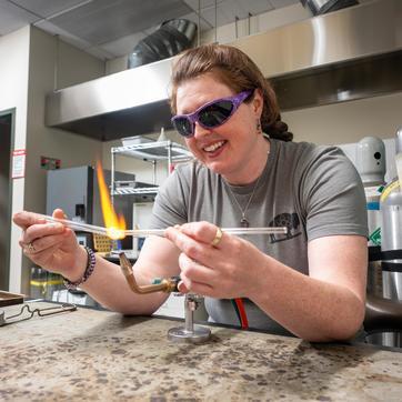 Researcher heating up glass tubes in lab