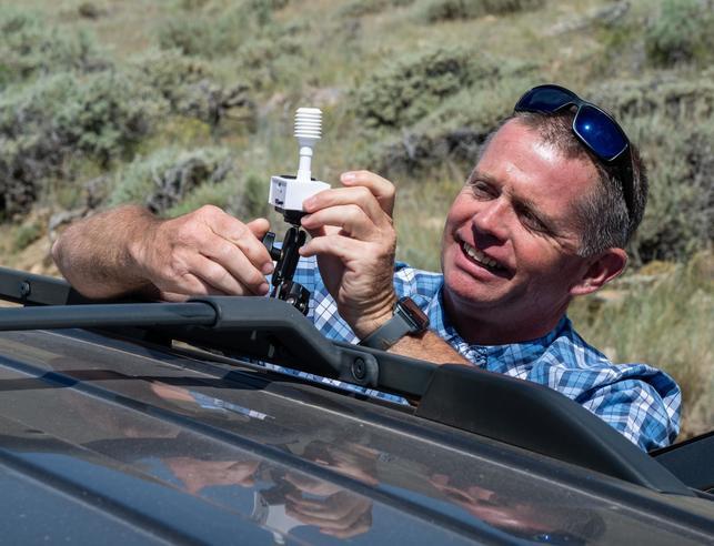 Researcher putting sensor on top of car at the Elk Mountain Observatory