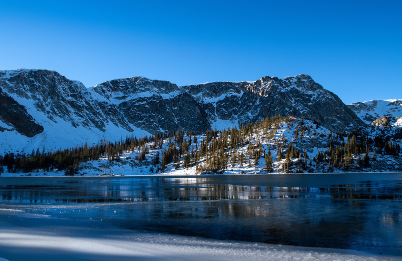 Medicine Bow Peak is outlined in front of a frozen lake in Medicine Bow-Routt National Forest.