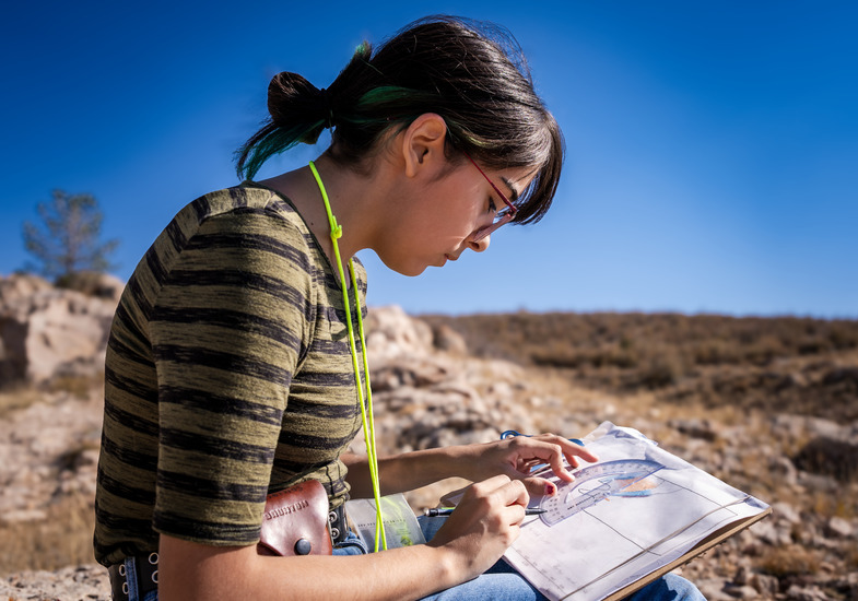 A researcher conducts field research in an outdoor area using a protractor, as part of the WYoming IDeA program.