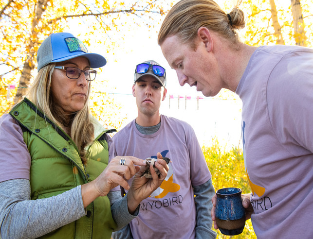 Faculty with two students in field with bird
