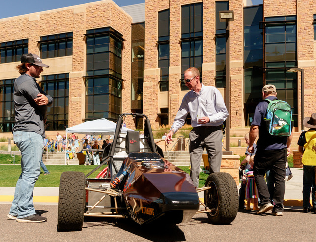 People looking at a small race car on campus