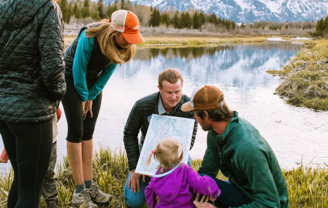 A group of people looking at a map next to a river