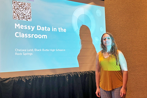 Teacher Chelsea Lund standing in front of a screen with her presentation