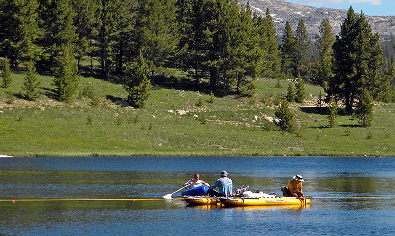 three researchers on a boat, taking samples in a lake