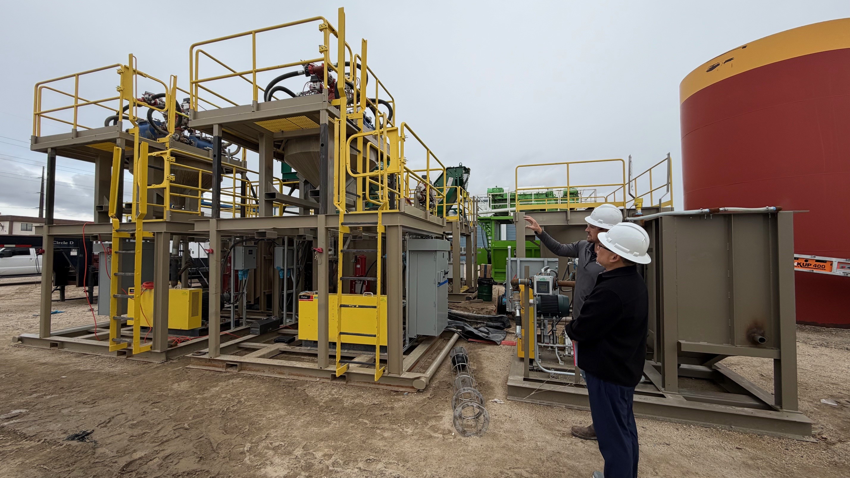 two men visit infront of machinering being used in the field