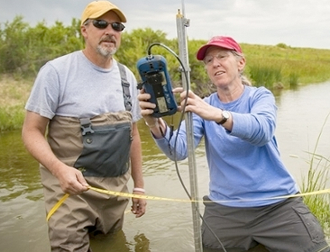 Two researchers in stream installing equipment