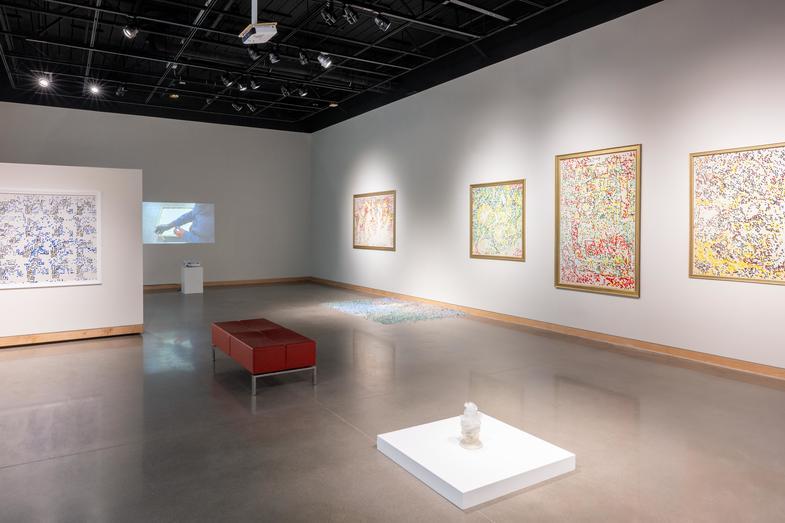 gallery with artwork haning on walls and stiting on platforms