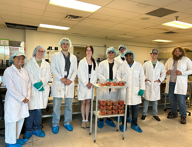 Class in lab coats standing and smiling