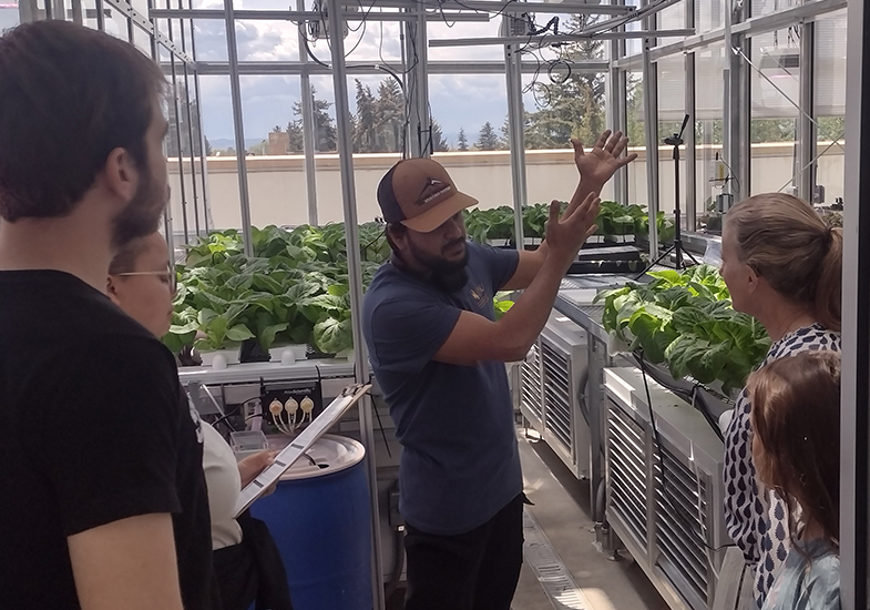 Person teaching about plants to three students in CEA