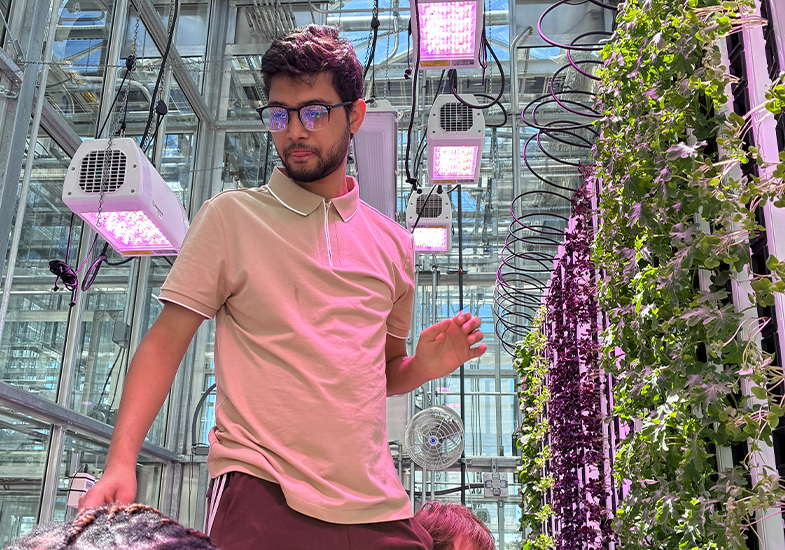 Student looking at plants next to vertical towers with plants