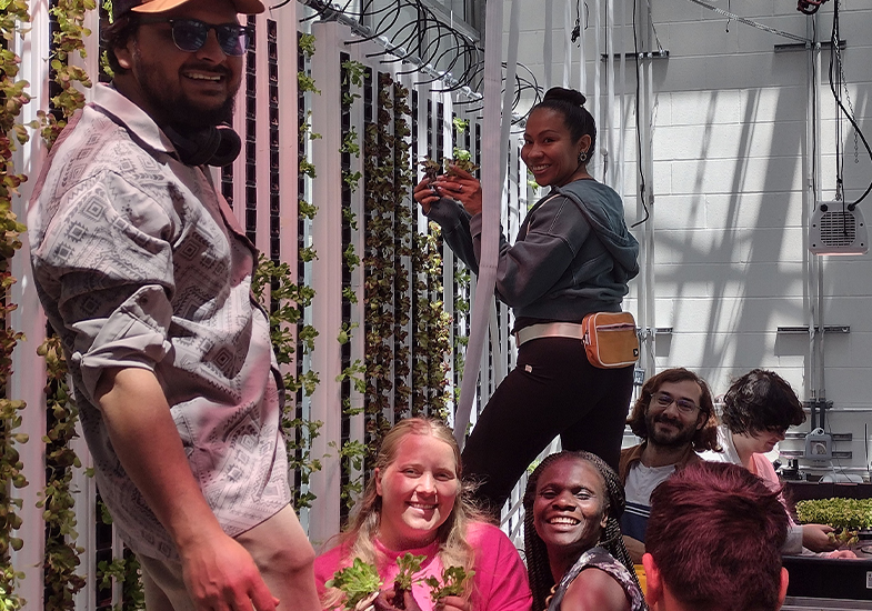 Students smiling in lab with plants and vertical growing towers