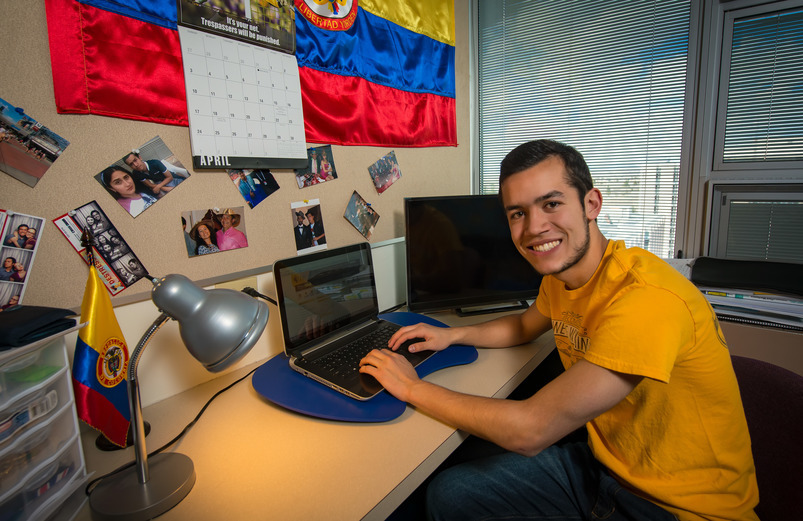 Student sits in front of his desk in residence halls
