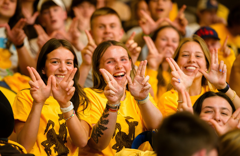 Two students smile at the camera in the stands at Saddle Up