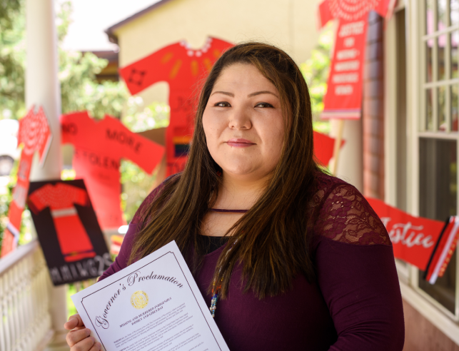 woman holding a sign while standing on a porch