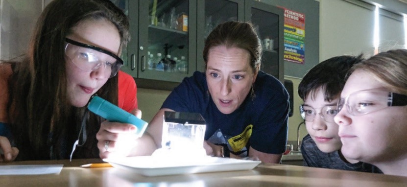 students watch a demonstration of a radiation based activity using a cloud chamber