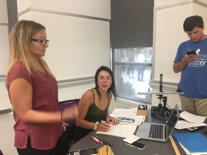 learning assistant talking to two students