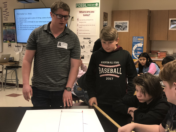 Joshua helps students sitting at a desk