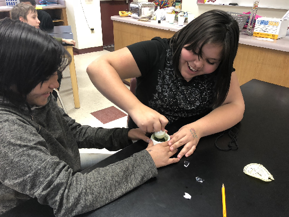 Students crushing green substance with mortar and pestle