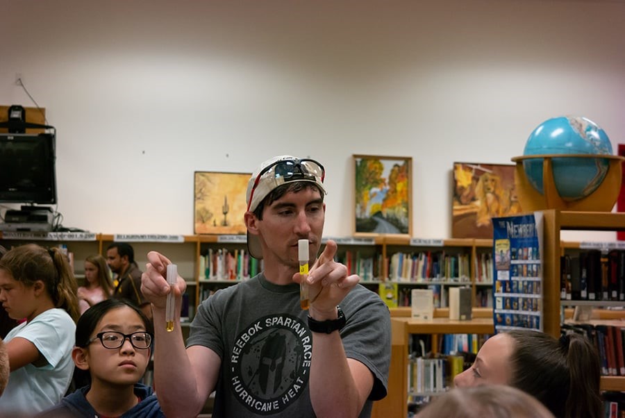 brian holding up two test tubes and talking to students