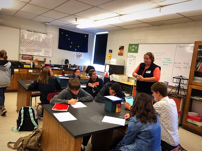 Becca talking with students while they are doing an activity