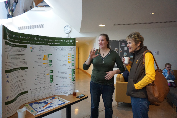 Two people talking in front of a poster